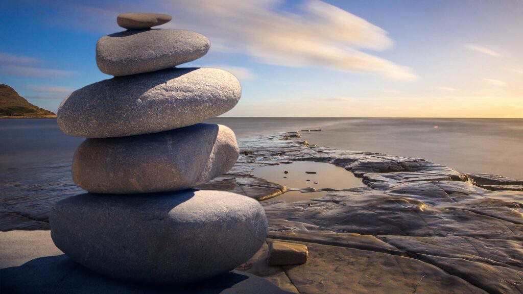 Balancing rocks on a beach, looking out into the ocean horizon.